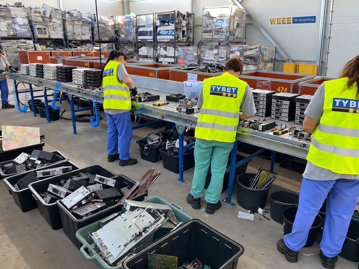 Workers manually dismantling telecom equipment at the TYBET OKO plant